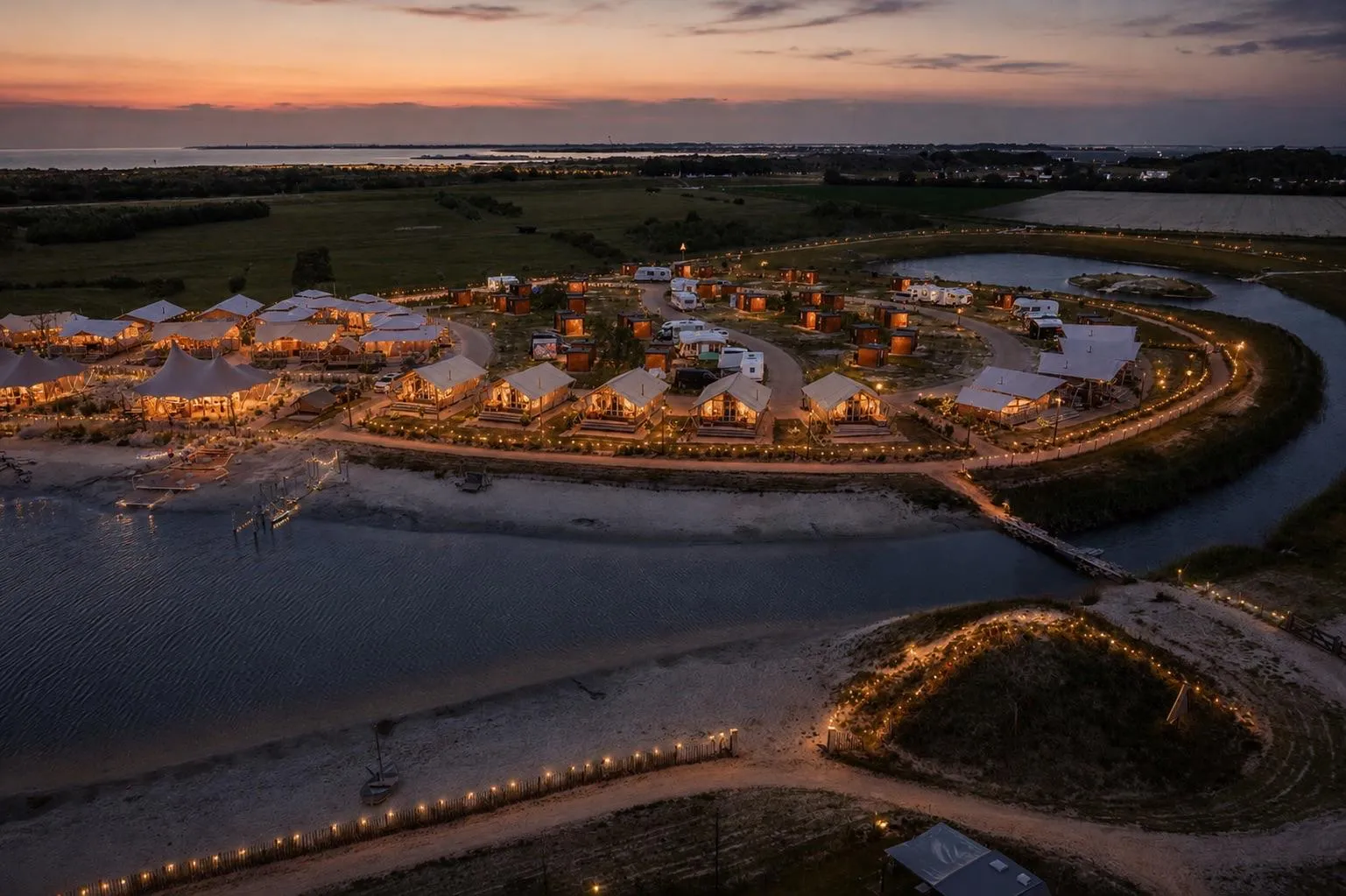 Luchtfoto van Strandpark De Zeeuwse Kust met verlichte tenten bij zonsondergang